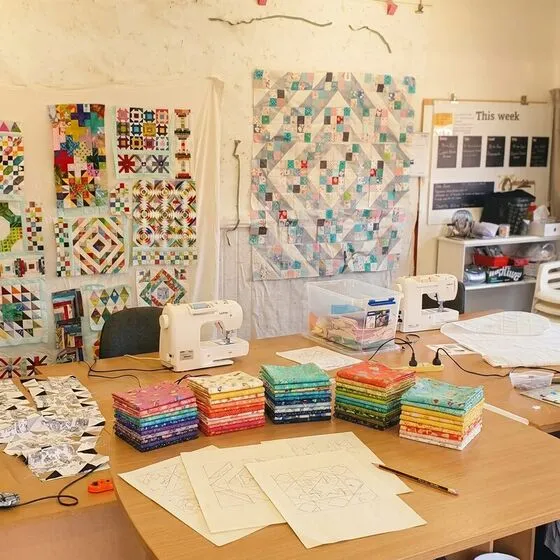 Folded quilting fabrics and block sketches on a table, planning a quilt